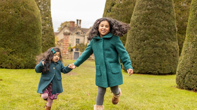 Girls run in the Yew Garden at Packwood House, Warwickshire